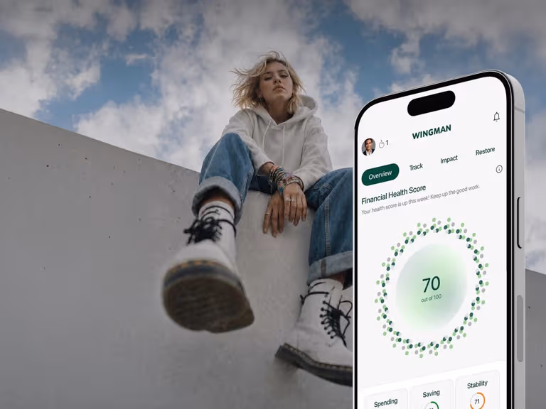 Wingman app showing a Financial Health Score of 70 out of 100 on a phone, with a young woman sitting on a concrete wall behind it