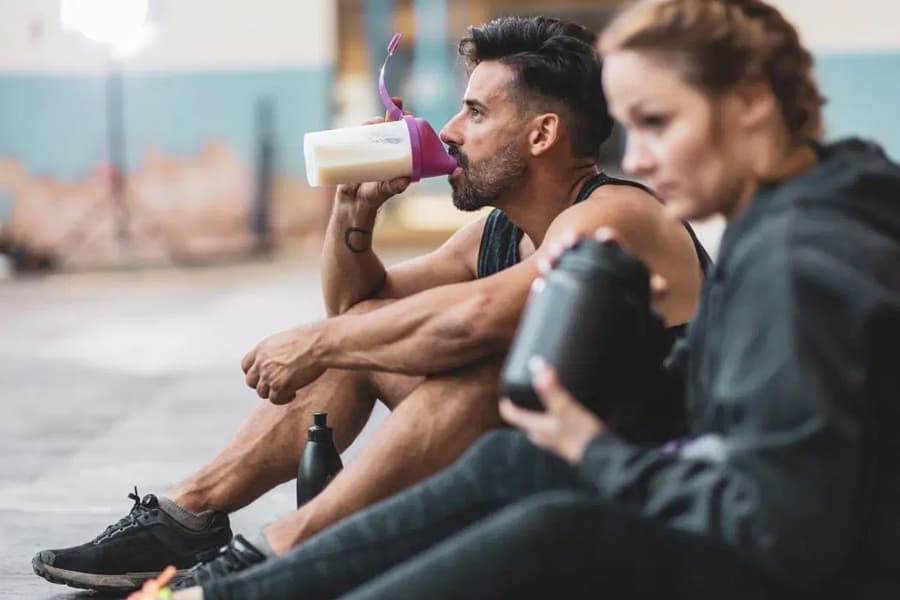 A man and a woman with shakers in their hands sitting on floor