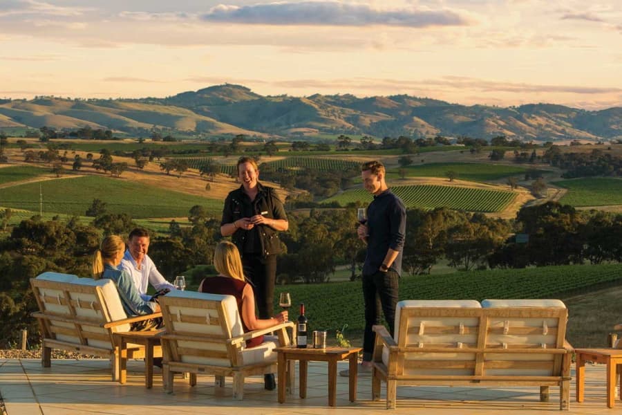 People at an open air lounge over a small mountain drinking wine