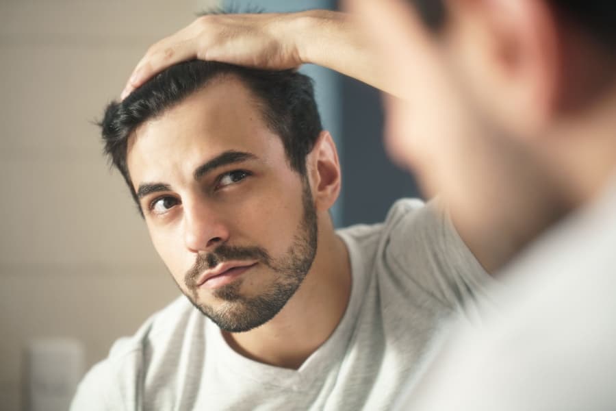 A man looking at his hairline in mirror