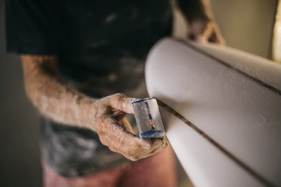 A hand doing finishing on a surfboard