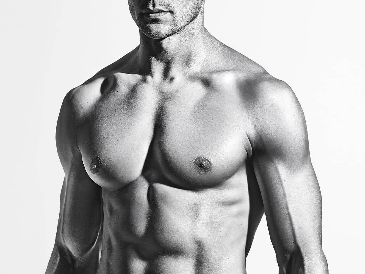 Greyscale close up of a muscular man’s bare chest