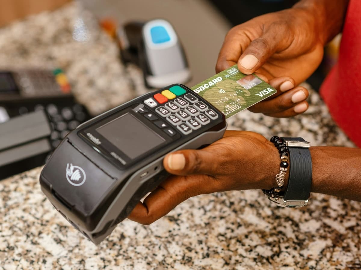 Person using a Visa card with an EFTPOS machine on a granite countertop.