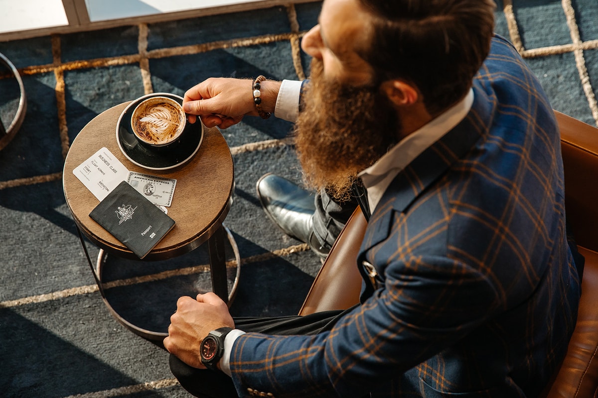 Top view of a man at a coffee table with Amex Platinum Card and passport on table