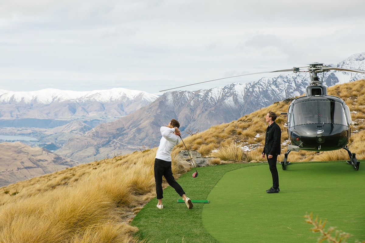 Jimmy playing golf on a mountain next to a helicopter hitting the ball down the mountain