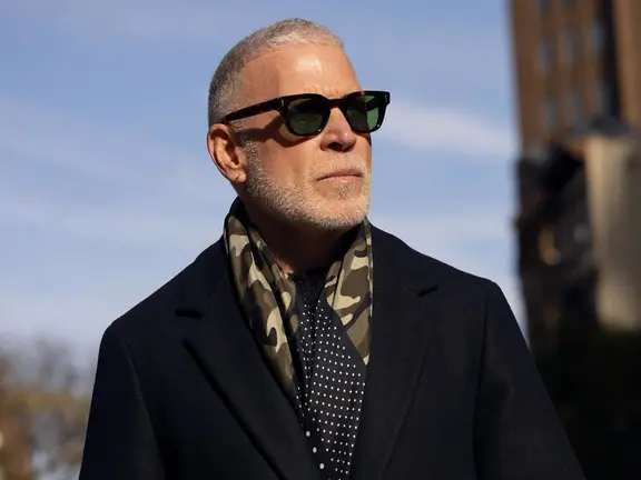 Nick Wooster wearing sunglasses, patterned scarf, black b;azer