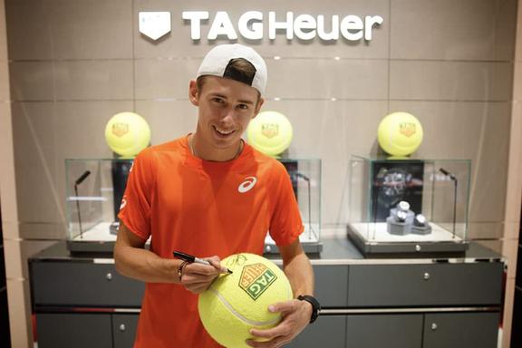 Alex de Minaur signing a big Tennis ball with TAG Heuer logo on it