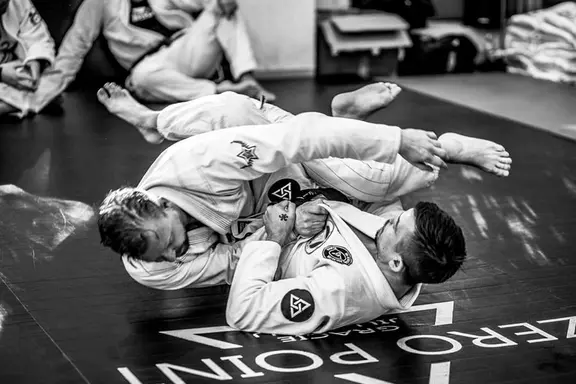 Two men practicing jiu jitsu on floor