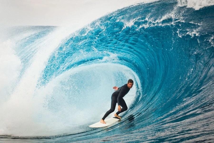 Surfer under a big wave arching over him
