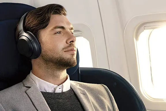 A man wearing headphones sitting on a flight seat