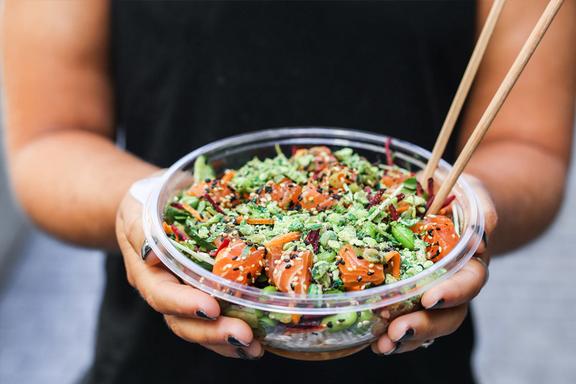 Pair of hands holding a poke bowl