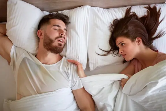 A man sleeping in bed next to an angry wife