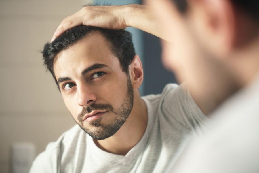 A man looking at his hairline in mirror