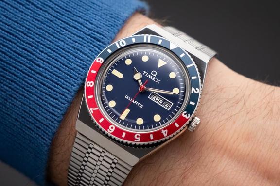 A red and blue Q TImex watch on a wrist