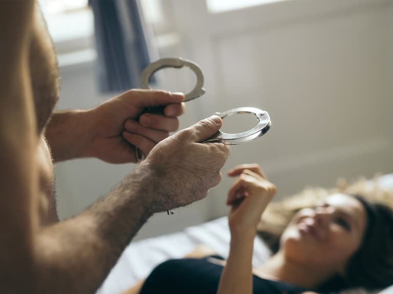 Man on top of woman holding handcuffs