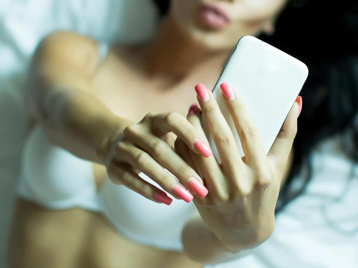 Woman in her underwear holding up a phone to take a selfie