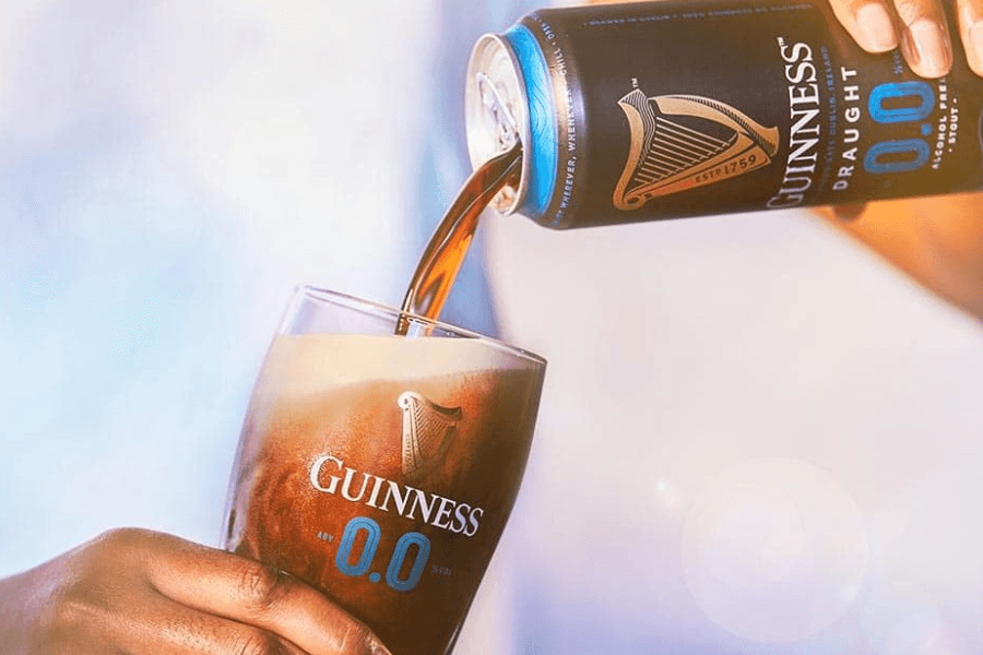 A hand pouring Guinness Non-Alcoholic Pint in a glass out of a can