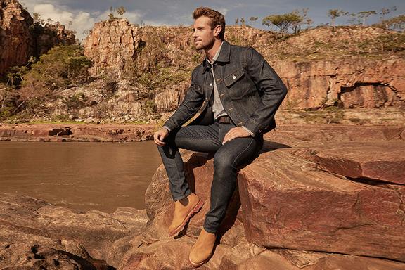 A man sitting on a rock in R.M. Williams new Summer Collection clothes