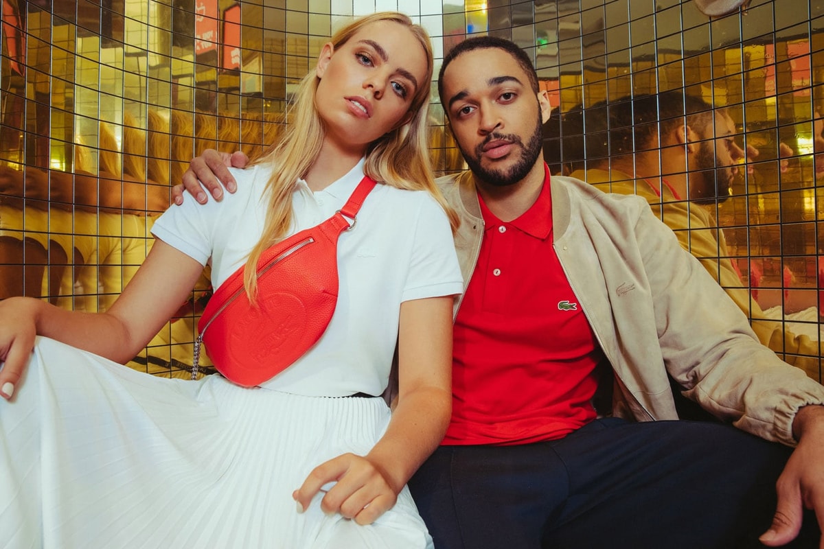 A man wearing a Lacoste polo t-shirt with his arm on a shoulder of a girl next to him wearing a Lacoste pouch around her chest