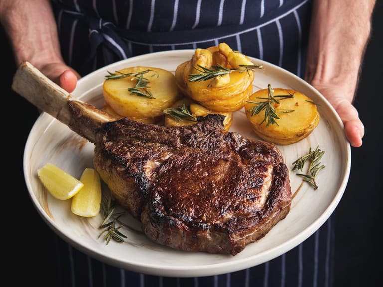 chef serving steak with potato in black hide steakhouse
