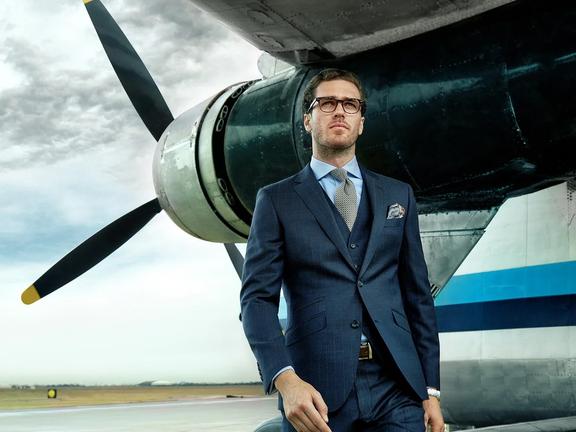 Man in a suit with a plane in the background