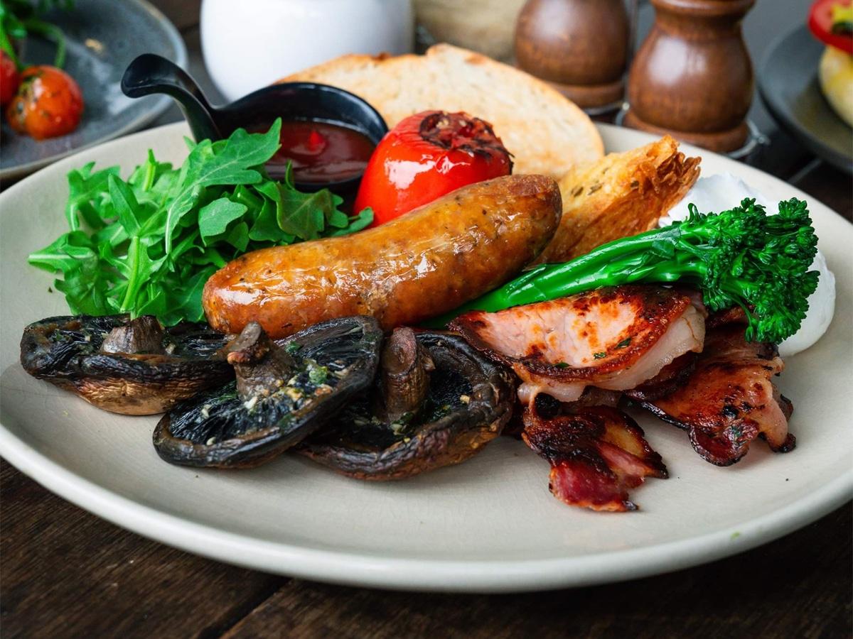 Sausage, mushroom, bacon, tomato, sliced bread, lettuce and ketchup on a plate