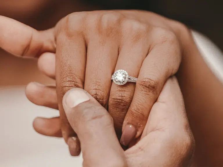 A hand holding someone's hand wearing an engagement ring