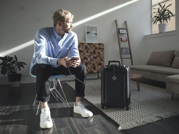 Man holding a phone charging from a suitcase