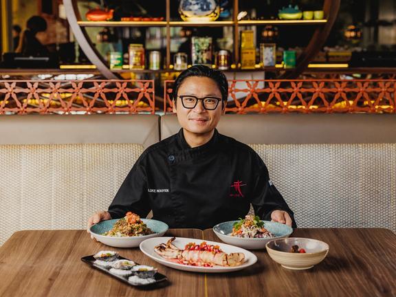 Chef Luke Nguyen sitting on a table with various dishes