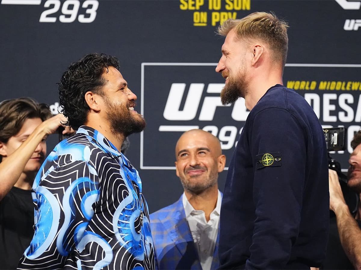 Tai Tuivasa and Alexander Volkov face off at UFC 293 weigh-in, both smiling, with a branded backdrop.