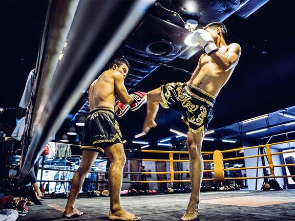 Low angle shot of two men sparring inside a muay thai ring