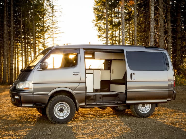Toyota Hiace on the road in the woods at sunset