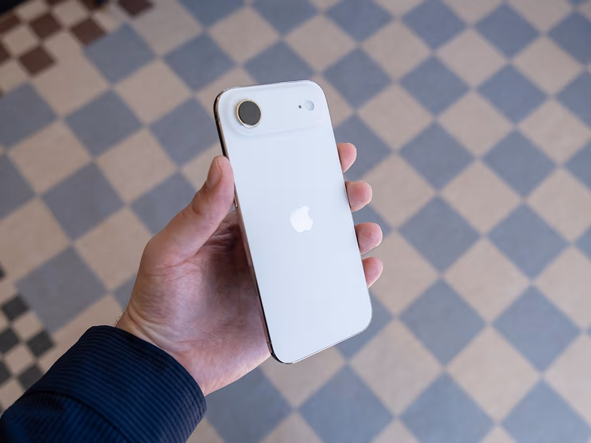 iPhone 17 Air in white held in hand, showcasing its sleek design and Apple logo against a tiled floor background.