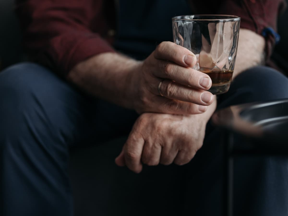 A man holding a whisky tumbler.