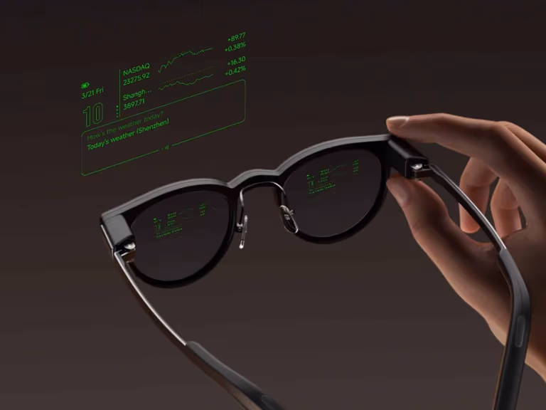 MemoMind One glasses held in one hand with green heads-up display text visible across both lenses