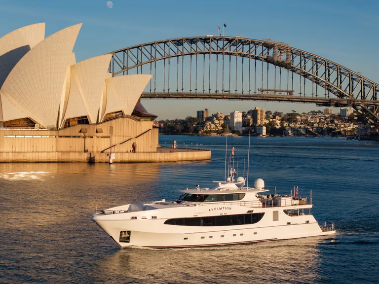 The superyacht Evolution cruising past the Sydney Opera House and Harbour Bridge