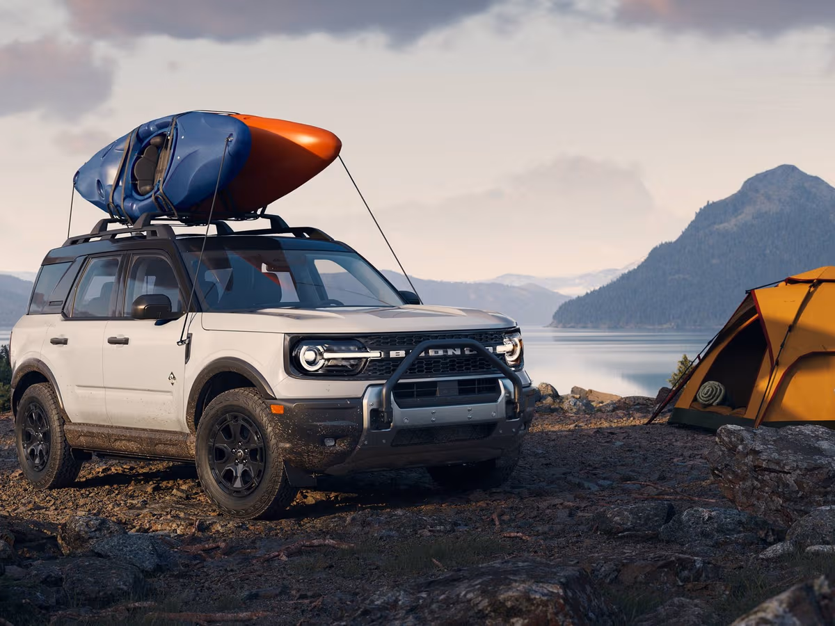 Ford Bronco Sport with a kayak on the roof at a lakeside campsite