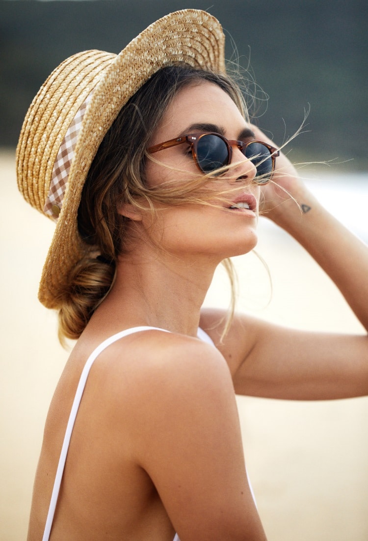 a woman is wearing hat and pacifico sunglass