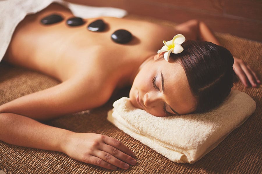 girl lying down with hot rocks 