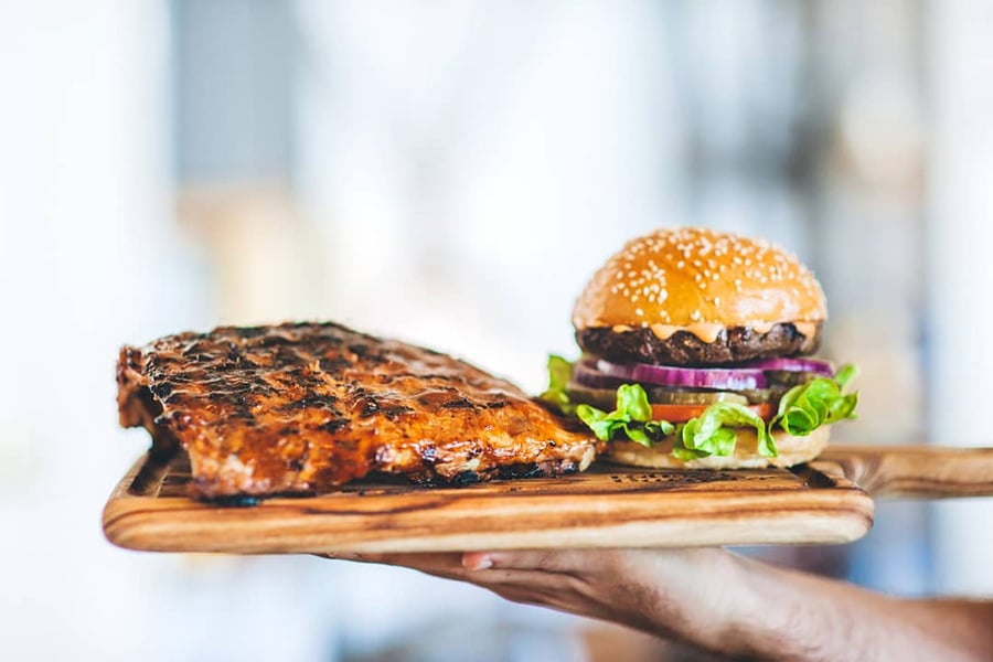 hand holding serving board ribs and burger