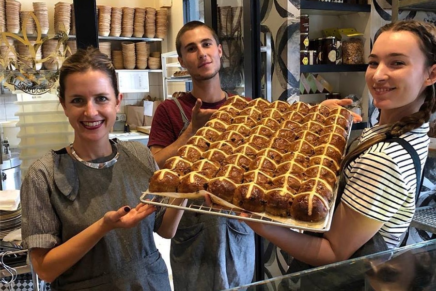 baker d chirico workers holding hot cross buns