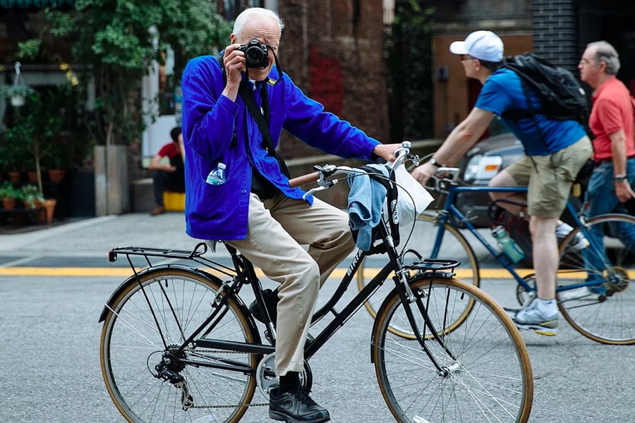 Bill Cunningham in blue jacket on bike