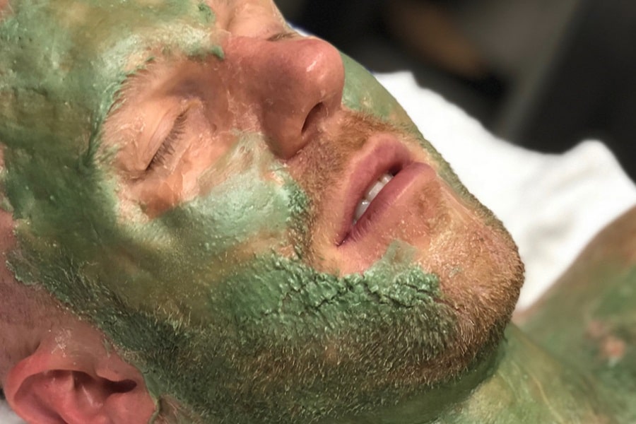 A man's face covered in green facial lotion
