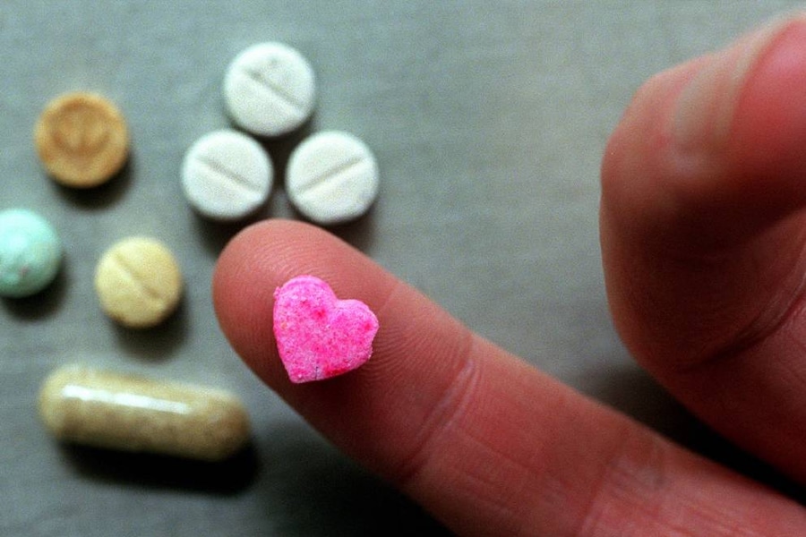 Pink heart pill on finger