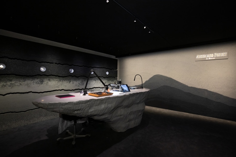 Audemars Piguet artistic watch display with sculptural desk and spotlighting in a dark exhibition room.