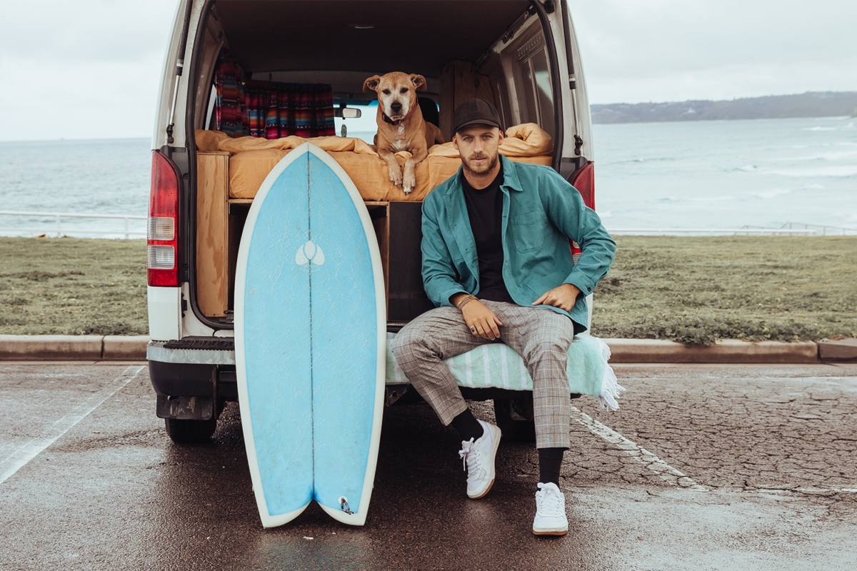 Mitch at the back of van next to his surfboard