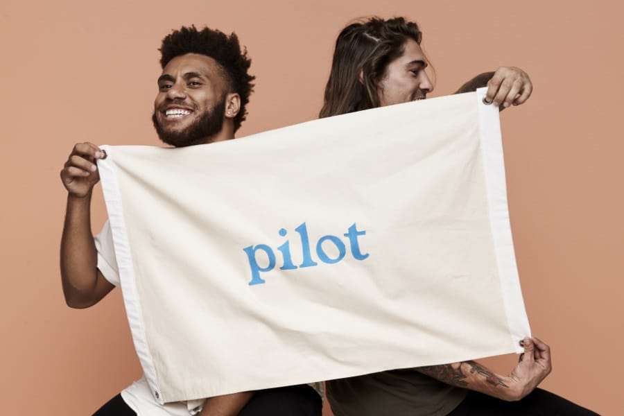 Two man holding a cloth with Pilot logo in center