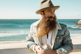 Man with a long beard with beach in background