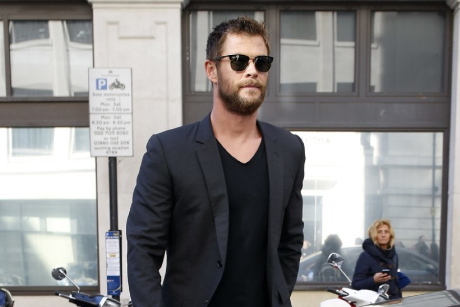 Medium shot of Chris Hemsworth in a black v-neck shirt and charcoal blazer wearing sunglasses