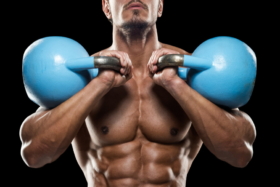 A man holding two kettlebells touching his shoulders